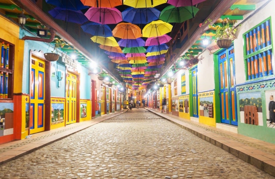 Una delle vie di Guatapé, in Colombia, di notte, con i suoi tipici edifici colorati, e degli ombrelli appesi in alto, tra i palazzi